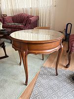 Full view of round accent table showing wood frame, glass top, cabriole legs
