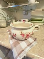 Side view of chamber pot showing floral decoration and handle