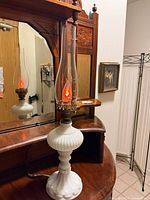 Full view of milk glass lamp with chimney and lit bulb
