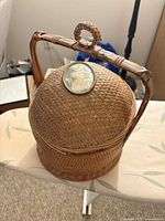 Full view of wicker basket with handle raised and portrait medallion visible