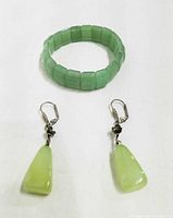 Stretch bracelet and pair of jade earrings displayed on white background