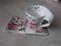 Teacup seated on matching rectangular saucer showing floral postcard design