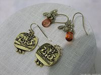Both pairs of brass earrings displayed, showing design details