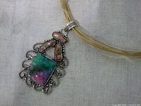 Front view of silver plated pendant with multicolor stone and mother of pearl on cord necklace