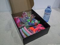 Open box showing LED plugs in plastic bags, assorted balloons and reference water bottle