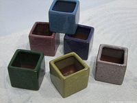 Six small square ceramic planters grouped together, view of openings