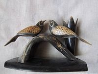 Front view of carved cow horn pen holder showing two birds on arched base and upright pen tube