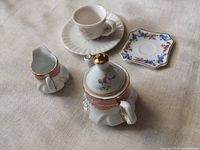 Miniature teapot, creamer, cup, saucer and square plate laid out