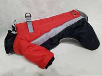 Side view of red and black dog overalls showing reflective stripe, D-ring and snap