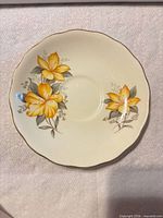 Front of saucer showing floral decoration, scalloped gold-trimmed rim