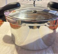 Front view of closed stainless steel pressure cooker showing polished body and lid