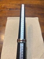 Dark grey band with rose-gold stripe shown on mandrel at size 9