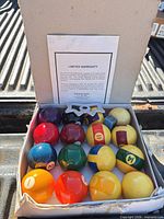 Open box showing full set of Aramith balls and warranty card