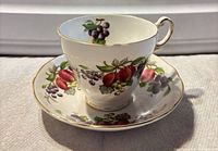 Front view of Regency teacup on saucer showing fruit pattern and gilded rims