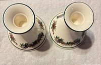 Top view of both ceramic candlestick holders showing green-rimmed openings and holly motif around bases