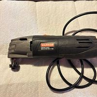 Left side view of Warrior oscillating multi-tool showing logo and cord