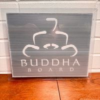 Front of sealed Buddha Board package showing logo and board