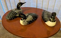 Three wooden loon carvings on table, side view