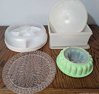 Group shot of all five items: covered dish, square container, clear platter, green mold