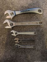 All five adjustable wrenches laid out to show size progression