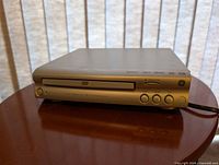 Front view of GE silver DVD/CD player showing disc tray, controls and branding