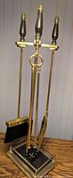 Full view of brass stand with four tools hanging