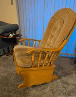 Side view of maple glider chair showing cushions, arm spindles and curved base
