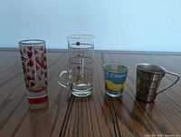 four assorted shot glasses on wood surface