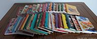 Full lot of 35 spiral-bound cookbooks arranged on table