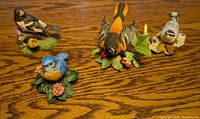 Group view of all four Lenox bird figurines on wooden surface
