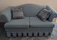 Front view of blue plaid loveseat with two pillows