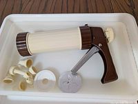 Cookie press with accessories in white trays