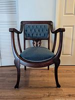 Full front view of Regency style chair showing wood frame, curved arms, blue upholstery