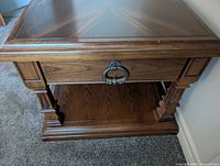 Angled view showing top, drawer front with ring pull, carved legs, lower shelf