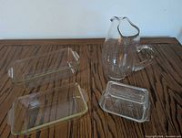 Lot overview showing water jug, two loaf pans, butter dish
