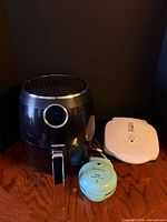 Gourmia air fryer, Nostalgia waffle maker, George Foreman grill grouped together
