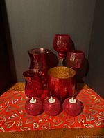 Group shot of all red glass candleholders/vases and heart runner