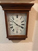 Front view of Howard Miller oak wall clock showing dial and case