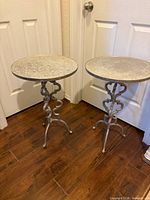 Pair of cast aluminum round top end tables against doors