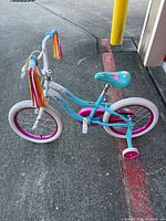 Left side view of Schwinn Iris 16-inch teal bicycle with training wheels and streamers