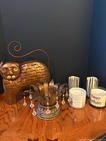 Front view of copper cat candle holder, silver crystal votive holder, two jar candles