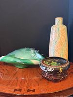 Group shot of glass shell, ceramic vase, cloisonné bowl on wooden surface