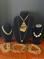 Group view of all gold-tone necklaces on display busts and table
