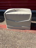 Closed hard plastic carrying case sitting on pavement
