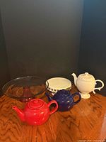 Group shot of three teapots and two cake stands
