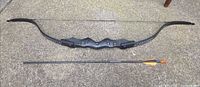 Full view of recurve bow and arrow laid flat