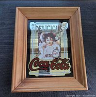 Frontal view of framed advertising mirror showing full graphic and wood frame