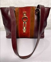 Front view showing leather sides, central suede panel, gold-tone ring and clasp hardware, strap