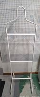 Full front view of white metal valet stand showing overall structure and rails