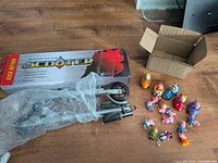 Boxed, wrapped scooter beside group of Peppa Pig toys